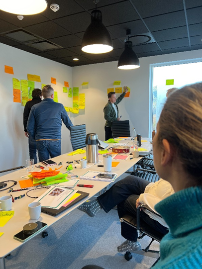 Byggmester hitland og Tidsbanken holder på med workshop. Det er mange lapper på veggene og deltakere står engasjert og peker