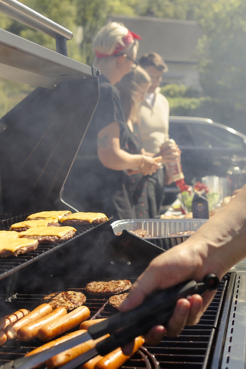 Bildet viser noen som griller og mennesker som spiser grillmat 