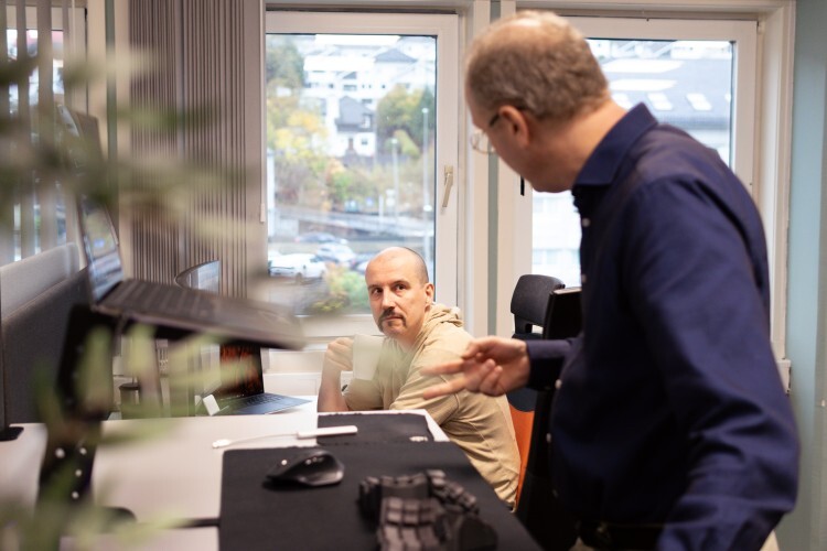 bildet viser to menn som jobber i et kontorlandskap.